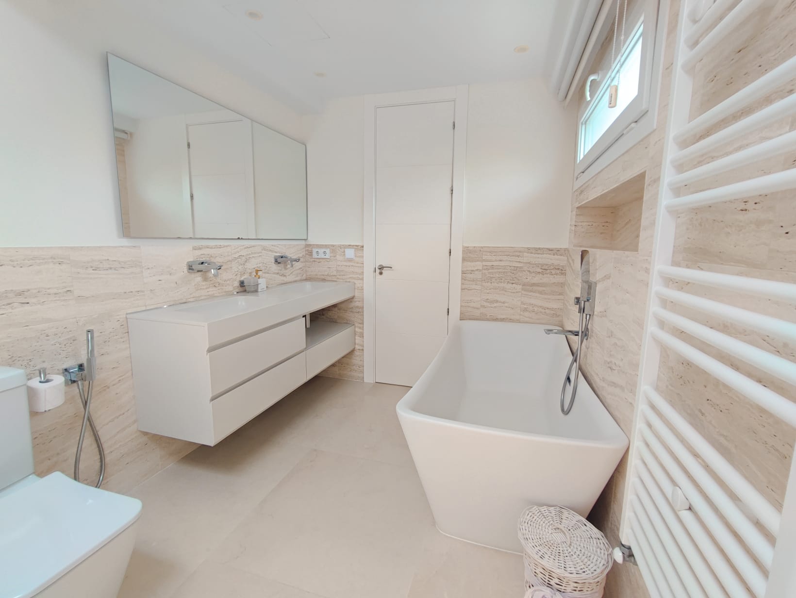 Travertine bathroom with freestanding bathtub and floating vanity