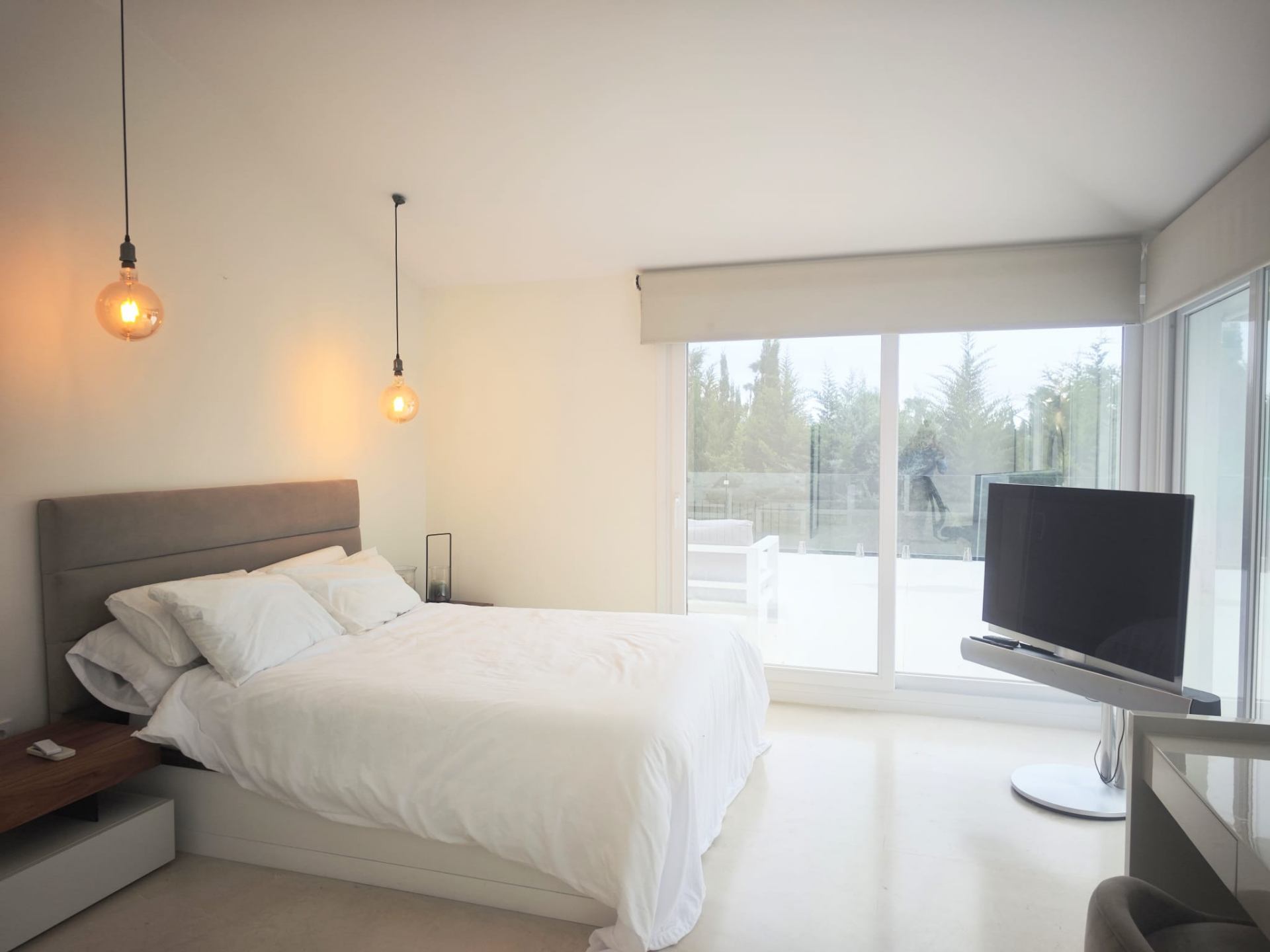 Bedroom with floor-to-ceiling glass opening onto a private terrace