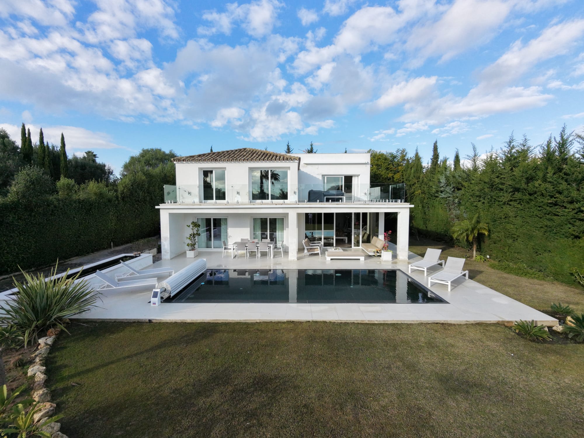 Villa exterior with infinity pool, manicured gardens and Andalusian sky
